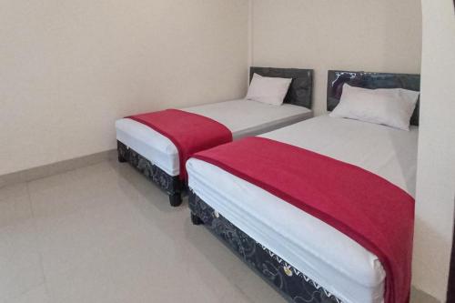 WeversdorpRedDoorz Syariah near Sentani City Square的两张睡床彼此相邻,位于一个房间里