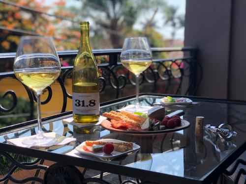 阿吉吉克Casa del Sol Inn的玻璃桌,带两杯葡萄酒和食物