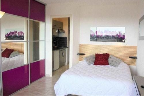 阿格德角Cap d'Agde Naturist Héliopolis O 33的卧室配有白色的床和紫色橱柜。