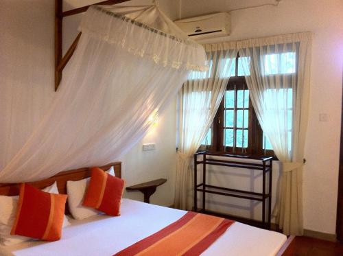阿努拉德普勒小天堂旅游宾馆度假屋的卧室配有带白色窗帘的床和窗户。