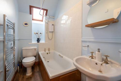 因弗内斯The 'Fairy Hill' Apartment的浴室配有盥洗盆、卫生间和浴缸。