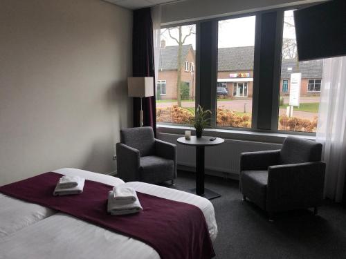 Ruinen库克酒店的酒店客房设有一张床、两把椅子和一扇窗户。