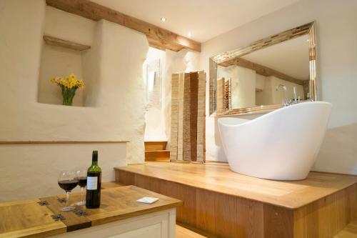 滕比萃芙乐庄园酒店的一间带白色浴缸和一瓶葡萄酒的浴室