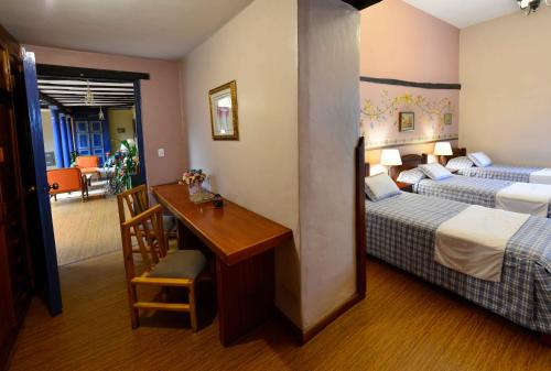 昆卡Hotel Posada del Angel的酒店客房设有两张床、一张桌子和一张桌子。