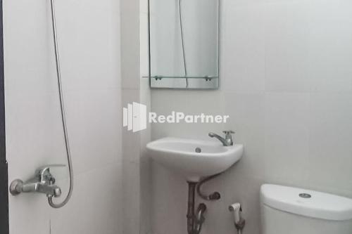 Poponcal 2Ardico Residence Syariah Mitra RedDoorz的一间带水槽、镜子和卫生间的浴室