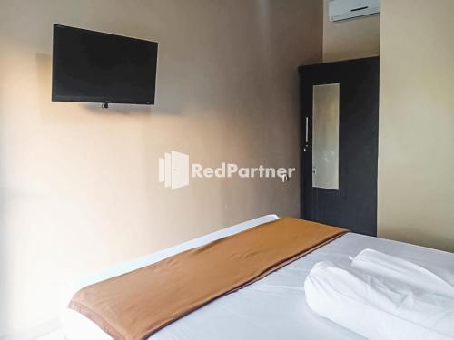 Poponcal 2Ardico Residence Syariah Mitra RedDoorz的卧室配有一张壁挂式平面电视的床。