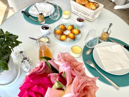 VillechétifVilla de la Croix的一张白色的桌子,上面放着食物和鲜花