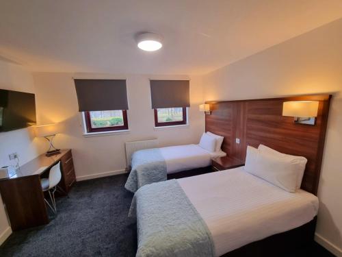 福尔柯克Premier Lodge的酒店客房配有两张床和一张书桌