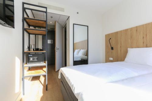 鹿特丹Fletcher Hotel Rotterdam-Airport的卧室配有一张白色大床和镜子