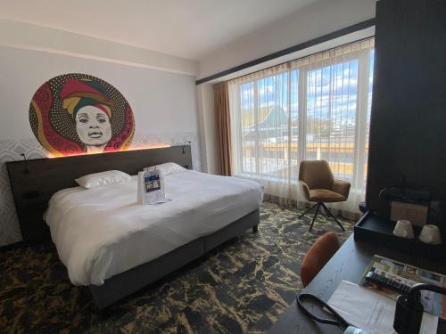 埃曼Fletcher Hotel-Restaurant ByZoo Emmen的酒店客房配有一张特大号床,墙上挂有绘画作品