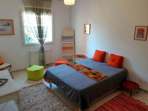 迦玛特Perle de Gammarth的一间卧室配有带橙色枕头的床和窗户。