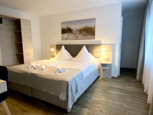 施坦胡德Hotel Kranenborgh Steinhude am Meer的一间卧室配有带白色床单和枕头的床。