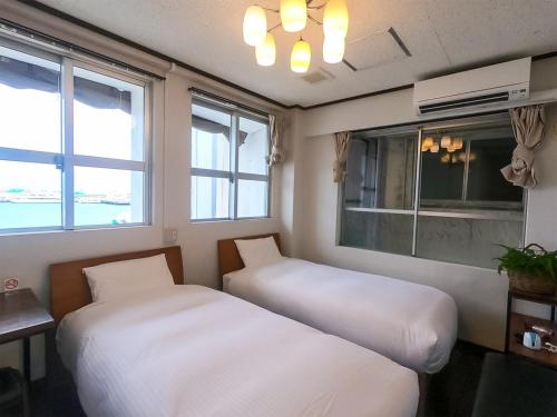 石垣岛石垣岛奥丽芙酒店的配有窗户的客房内的两张床