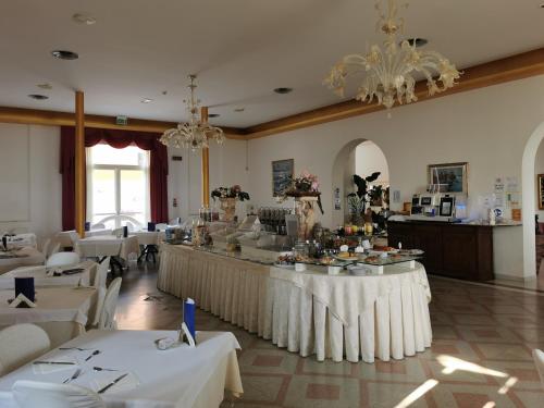 里米尼Hotel Lido的餐厅配有白色的桌椅和吊灯