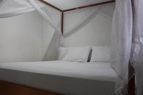 San Juan de AramaSerranía Eco Lodge的白色的床、白色枕头和天蓬