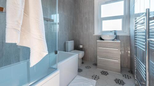 纽波特Tŷ Hapus Newport - Luxury 4 Bedroom Home的带浴缸、卫生间和窗户的浴室
