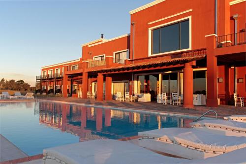 圣安东尼奥德阿雷科Pampas de Areco Resort de Campo & Spa的一座带游泳池的大楼,毗邻一个度假胜地