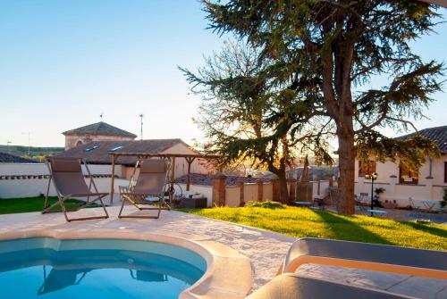莱尔马Hotel Rural El Cedro的一个带两把椅子和一棵树的游泳池