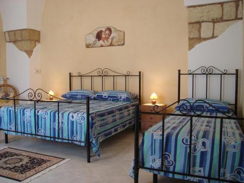 Montesano SalentinoLa Corte Antica的卧室配有两张床,墙上挂着一幅画