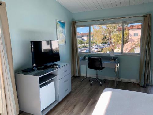 圣巴巴拉东海滩酒店的一间卧室配有电视、书桌和窗户。