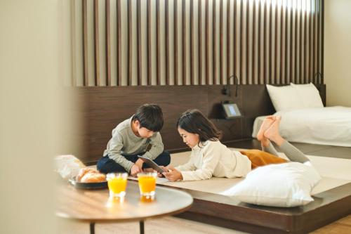 高松FAV HOTEL TAKAMATSU的坐在酒店房间地板上的男女