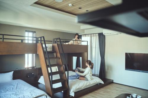 高松FAV HOTEL TAKAMATSU的两个女孩坐在卧室的双层床上