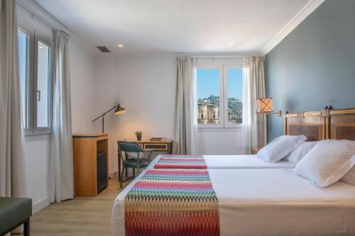 马拉加邓卡罗酒店的酒店客房设有一张床、一张书桌和窗户。