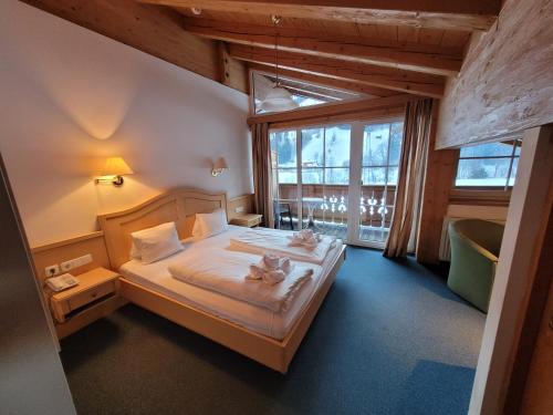 基茨比厄尔附近奥拉赫Ferienhotel Alpenhof的一间卧室,配有一张床铺,上面有两只猫