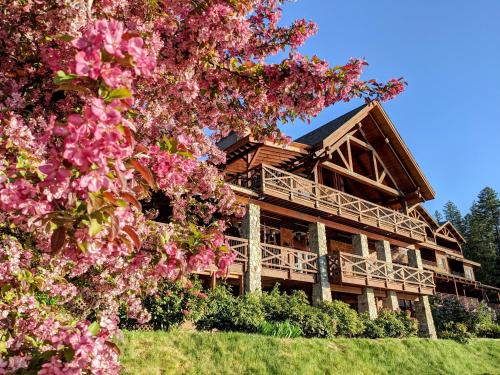 桑德波因特桑德珀恩特小屋酒店的一座大型的木制房子,前面有粉红色的花朵