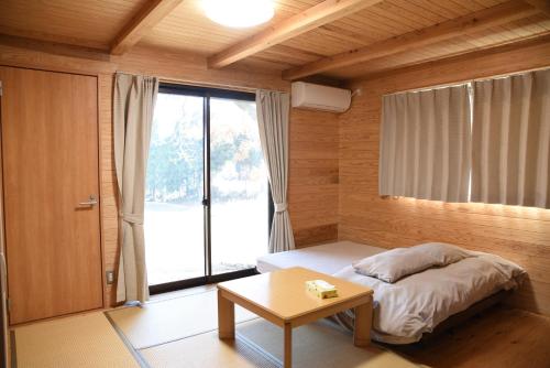 南阿苏村瓦卡旅馆的一间卧室配有一张床、一张桌子和一个窗户。