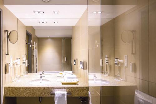 曼海姆Lanzcarré Hotel Mannheim, a member of Radisson Individuals的一间带两个盥洗盆和大镜子的浴室