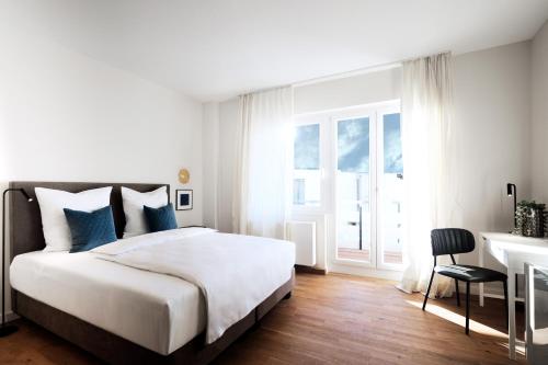 哈根SAXX Apartments Hagen的白色卧室配有床和书桌