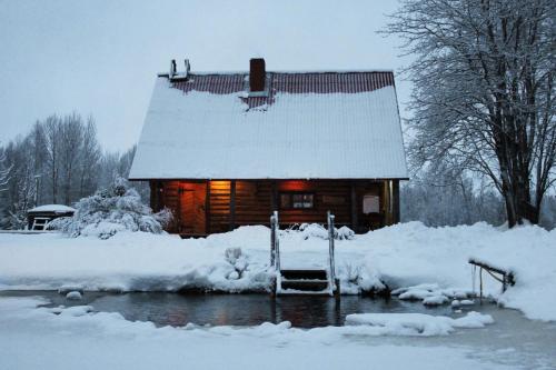 SīveciPirts Baudas的雪中的一个小木屋,灯光照亮