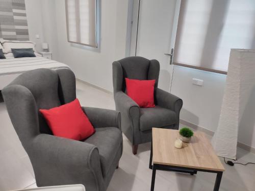 马德里Apartamento Madrid Norte的一间卧室配有两把椅子和一张带红色枕头的床