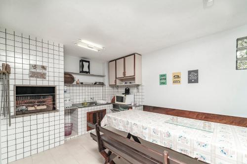 邦比尼亚斯Casa na praia de Morrinhos Bombinhas para 10 pessoas, Excelente localização的厨房设有白色瓷砖墙壁和木凳