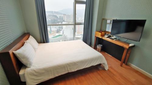 首尔Myeongdong Merlin Hotel的配有一张床和一台平面电视的酒店客房