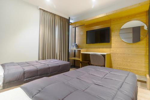 新德里Hotel Bricks, Karol Bagh, New Delhi的一间卧室配有两张床、一张桌子和一台电视。