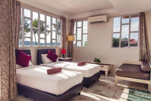 珍南海滩Sandy Beach Resort By Casa Loma的一间卧室设有两张床、一张桌子和窗户。