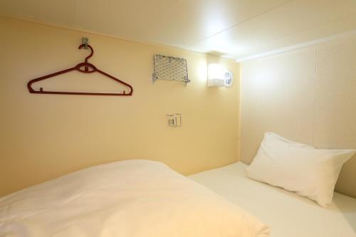 北九州Meimon Taiyo Ferry 1st sailing from Kitakyushu to Osaka的一间小卧室,配有白色的床和衣架