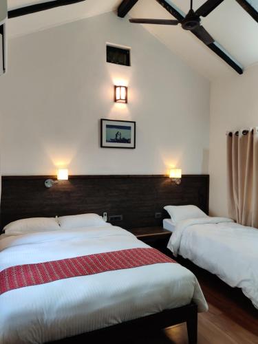 BardiyāBardia Forest Resort的一间卧室配有两张床,墙上有两盏灯