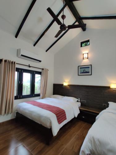 BardiyāBardia Forest Resort的配有白色墙壁和木地板的客房内的两张床