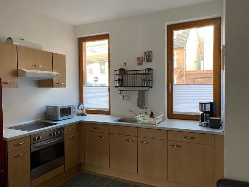 罗斯托克Hofquartier的厨房配有木制橱柜、水槽和微波炉