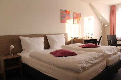 雷马根APTE莱茵酒店的一间卧室配有两张带白色床单和红色枕头的床。