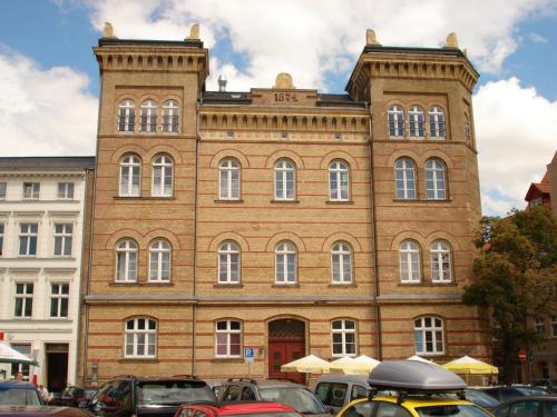 施特拉尔松德施特拉尔松德老城区城市公寓酒店的一座大型砖砌建筑,前面有汽车停放