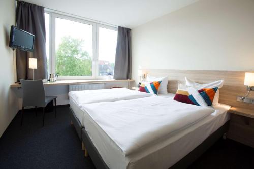 不来梅港弗洛登齐尔大西洋酒店的酒店客房设有一张大床和一张书桌。