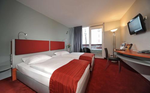 不来梅港Nordsee Hotel Fischereihafen的酒店客房配有一张床、一张书桌和一台电视。