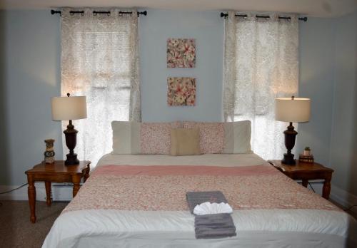 AdrianCozy 2nd story Flat near downtown的一间卧室配有一张带两盏灯的床和两扇窗户。
