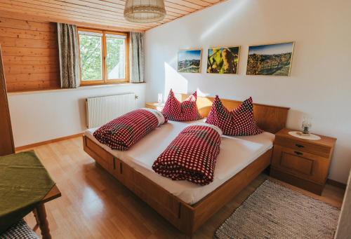 加姆利茨Gästezimmer & Buschenschank mit Weingut Hack-Gebell的一间卧室配有红色和白色枕头的床