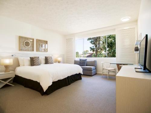 卡伦德拉Oaks Sunshine Coast Oasis Resort的一间卧室配有一张床、一张沙发和一台电视