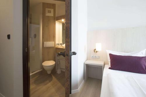 不来梅港Nautic Hotel Bremerhaven的一间卧室配有一张床,浴室设有卫生间